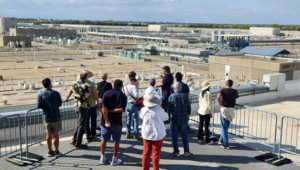 An image of a group of people turned away from the camera on the roof of a building looking at SacSewer's EchoWater Resource Recovery Facility.